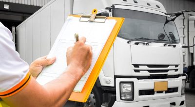 empleado-anotada-datos-en-un-almacen-frente-a-un-camion-de-autotransporte